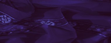 Görüntü, örülmüş aksanlı mor kumaş ve çarpıcı geometrik arkaplan, zengin doku ve zarif bir bitiş..