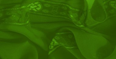 Işıldayan detaylar ve akan kıvrımlarla süslenmiş canlı yeşil bir kumaşın bulanıklığı büyüleyici bir doku ve parlak desenler karışımı yaratır.