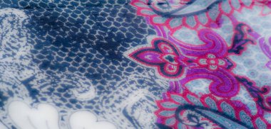 Karmaşık desenler ve canlı renkler içeren canlı kumaşın yakın plan görüntüsü. Katlar ve doku zarif tasarıma derinlik ekler.