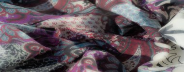 Koyu mavi ve gri tonlarda katmanlı yılan derisi dokuların bulanık ve soyut tasviri, akan katlarla modern ve cesur bir estetik sunuyor..