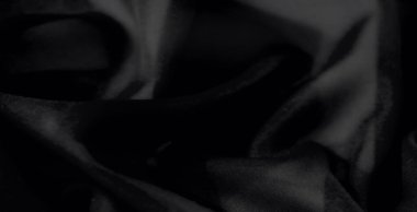 Pürüzsüz siyah kumaştan oluşan, kıvrımlı ve zengin bir kaplama, yaratıcı ya da modaya uygun projeler için lüks ve çok yönlü bir arka plan oluşturur..