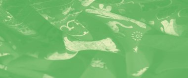 Beyaz çiçek desenli yumuşak yeşil bir kumaşın bulanık görüntüsü. Kumaşın pürüzsüz, narin dokusu karmaşık kıvrımlarıyla zarafet katıyor..