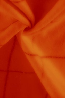 Bu turuncu kumaş görüntüde yumuşak kıvrımlar ve kesişen koyu çizgiler var, dinamik dokular ve zengin, sıcak tonlarla canlı bir görüntü oluşturuyor..