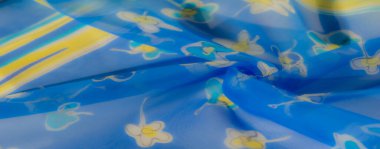 Bulanık efekt, çiçek sarısı ve beyaz desenli, parlak mavi renkli yumuşak, akan kumaşı güçlendirir. Hafif malzeme, cazibe ve entelektüellik hissi yayar..