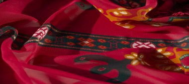 Karmaşık sarı ve turuncu çiçek desenli, koyu yeşil motifli bulanık kırmızı kumaş. Detaylı tasarım yumuşak dokuları ve katmanlı görünümü vurgular.