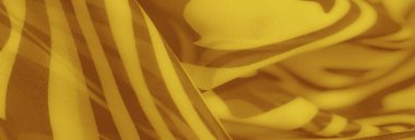 Altın renkli tekstilin doğal hatları ve soyut formları, tasarım ilhamı veya ürün gösterimi için ideal sıcaklık ve akıcılığı çağrıştırır..