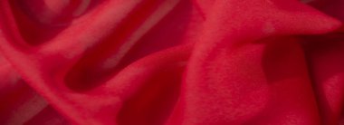 Pürüzsüz, parlak kıvrımları ve yumuşak dokusu olan kırmızı bir kumaş. Sıcak, zarif bir kompozisyonda canlı renkler ve gölgeler yaratıyor..