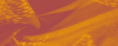 Görüntü, turuncu renkli kumaşın şık bir düzeni sıcak ve davetkar bir dokuyu yakalar. Işık ve gölgenin karışımı karmaşık desenler ortaya çıkararak tekstil sanatı ve dekoruna karmaşıklık katıyor..