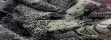 Çelişkili mor, mavi ve kırmızı kumaşlı bir kumaş. Karmaşık çiçek ve desenlerle eşleştirilmiş. Eşsiz ve canlı bir tekstil sergiliyor..