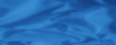 Bulanık ve katlanmış mavi kumaş zarif bir şekilde akar. Tekstil, ev dekorasyonu veya moda tasarımlarında yaratıcı kullanım için yumuşak dalgalar ve yumuşak dokular sergiler..