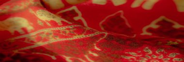 Üzerinde altın filler ve çiçekten esinlenilmiş detaylar olan bulanık kırmızı kumaş, muhteşem ve sofistike bir görünüm yaratıyor dekor veya giysi tasarımı için mükemmel.
