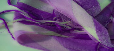 Pırıl pırıl parlak ve yıpranmış ipliklerle akan mor ve beyaz bir kumaşın bulanık görüntüsü. Dinamik doku yumuşak maddeye hareket ve boyut ekler..