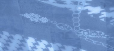 Pürüzsüz ve akan mavi kumaş zincir desenleri ve soyut şekillerle süslenmiş yumuşak dokuların ve zarif tasarımın uyumlu bir karışımını oluşturuyor..