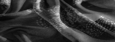 Bulanık, gelişmiş gri tonlu, kıvrımlı ve ince desenli kumaş. Tek renkli tonlar ve ışıklandırma sakin, minimalist bir estetik yaratıyor..