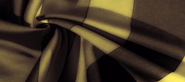 Görüntü. Sarı ve siyah kumaş pürüzsüz, dalgalanan kıvrımlar ve belirgin çapraz desenler, sıcaklık ve karanlığı minimalist, çağdaş bir tasarımda birleştiren.