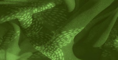 Görüntü yeşil kumaşa yumuşak, doğadan esinlenilmiş tasarımı ve sakin görünümünü vurgulayan akışkan kıvrımlar ve organik bir desen ekliyor..