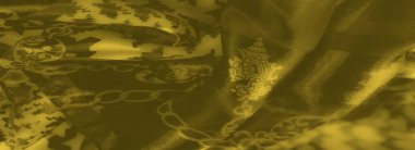 Karmaşık zincir ve houndstooth desenleri içeren sarı kumaşın bulanık yakın plan görüntüsü benzersiz bir estetik yaratıyor..