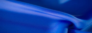 Görüntü zarif ve soyut bir görüntü oluşturur. Yumuşak mavi kumaş kıvrımlı, hassas ışık ve gölge oyunlu, dokuyu ve derinliği çağrıştıran..