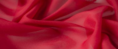 Yumuşak kırmızı kumaşın bulanık görüntüsü ince bir dokuya sahip, canlı tonlara ve pürüzsüz çizgilere sahip, tekstil, arkaplan veya yaratıcı projeler için mükemmel.