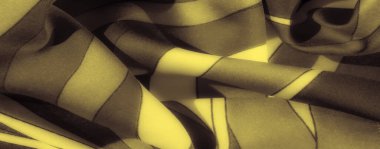 Süpürme çizgileri ve ipeksi yumuşak dokusu olan bulanık siyah ve sarı kumaş. Yüzeydeki ışığın etkileşimi, kumaşların lüks ve zengin görünümünü vurgular.