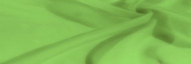 Yumuşak, katmanlı kıvrımlarla kıvrılmış yeşil kumaş bulanıklığı. Yumuşak tekstil, ışık ve gölgenin dengeli bir etkileşimini sergiliyor.