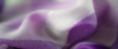 İnce krem tonlarıyla iç içe geçmiş mor kumaş, dinamik parıldayan dokular ve karmaşık ve lüks bir cazibe sunan gevşek iplikler..