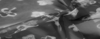 Bulanık gri tonlu görüntü şeffaf kumaş üzerinde narin çiçek desenleri gösteriyor. Katlar ve dokular yumuşak, zarif bir ışık ve gölge etkileşimi yaratır..