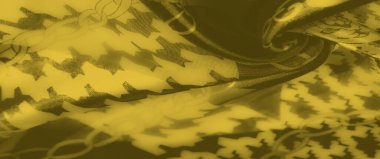 Birbirine dolanan zincir ve geometrik desenli yumuşak sarı kumaş bulanıklığı. Katların dinamik akışı bu karmaşık tekstil tasarımına derinlik ve enerji ekler..