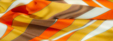 Kalın turuncu, sarı ve kahverengi çizgili kumaş üzerinde bulanık bir etki, ince mavi çizgilerle ayrılmış. Katlanmış tekstil pürüzsüz, akışkan desenler gösteriyor. Sıcak ve dekoratif estetik için ideal..