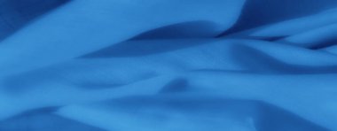 Yumuşak mavi kumaş kıvrımları ince gölgeler ve röflelerle zarif bir doku yaratır. İnce dokuma ve huzur verici, dingin estetiği vurgular..