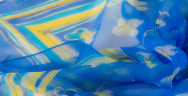 Görüntü, sarı ve beyaz çiçekli canlı mavi bir kumaş yakalar ve hafif dalgalarla yumuşak ve havadar bir doku oluşturur..