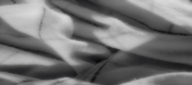 Bulanık gri ölçekli kumaş pürüzsüz kıvrımlar ve ince çizgiler içerir, minimalist bir estetik için ışığın ve gölgenin soyut ve rafine etkileşimini vurgular..