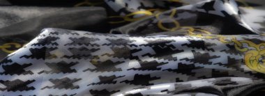 Çiçekli aksanlar ve çizgili detaylarla süslenmiş turuncu kumaşın yumuşak kıvrımlarını bulanıklaştırarak sanatsal dekor için canlı ve zarif bir tekstil oluşturuyor..