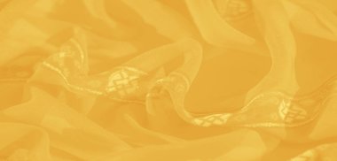 Karmaşık çiçekli ve geometrik desenli çarpıcı sarı bir kumaş, parıldayan detayları genel estetik cazibesine derinlik ve zarafet katıyor..