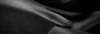 Yumuşak kıvrımları ve ince gölgeleri olan dalgalı siyah kumaş. Düz doku ve ipeksi dalgalar zarif ve sanatsal bir kompozisyon sağlar.