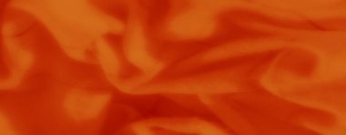 Bulanık - Kesişen ızgara çizgileri olan yumuşak turuncu bir kumaşın yakın çekim görüntüsü, pürüzsüz kıvrımlar ve gölgelerle sıcak ve dokulu bir görünüm yaratıyor.