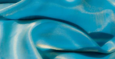 Pürüzsüz bir turkuaz kumaş, parlak, yansıtıcı ışıklar ve ince kırışıklıklar, sanatsal, moda veya tekstil tasarımı için ideal zarif bir doku yaratıyor..