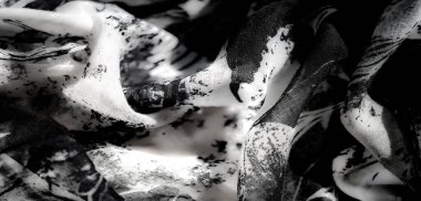 Yeşil röfleli siyah ve beyaz kumaşın bulanık detaylı görüntüsü, katmanlı desenleri ve zarif akış tarzını gözler önüne seriyor..