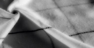 Bulanık, tek renkli kumaş, düzgün kıvrımlı ve geometrik siyah ızgara desenli. Işık ve gölge, maddedeki yumuşak ve detaylı kıvrımları vurgular.