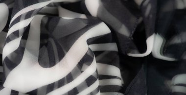 Dinamik girdaplar ve soyut desenler içeren pürüzsüz siyah beyaz kumaş bulanıklığı, yaratıcı projeler veya arka planlar için şık ve zarif bir dokunuş sağlıyor