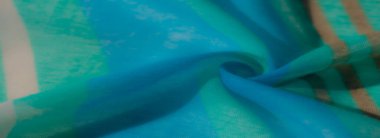 Pürüzsüz, yansıtıcı kıvrımlarla kaplı parlak mavi kumaş bulanıklığı. Doğal ışık ve gölgeyle zarif bir şekilde oynayan parlak ve ipeksi bir doku sergiliyor..