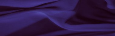 Yumuşak kıvrımları ve akışkan dokuları ile zengin mor kumaş bulanık yakın plan, karmaşık kıvrımlar ve hassas ışıklandırma mükemmel tekstil veya tasarım için.