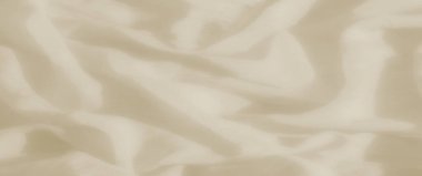 Hafif kıvrımlı açık bej kumaş bulanıklığı yumuşak, akıcı bir doku yaratıyor. Açık renk gölgeler derinlik ekler ve kumaşın yüzeyine yumuşak ve dingin bir kalite katar..
