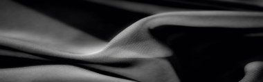 Bulanık, yumuşak kıvrımlı zarif siyah kumaş ve hafif ışık yansımalarıyla vurgulanmış pürüzsüz doku. İnce gradyanlar maddenin hassas örtüsünü vurgular..