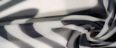 Görüntü, koyu siyah beyaz dalgaların olduğu zarif bir kumaş. Doku ve ışığın karmaşık etkileşimi zamansız ve sanatsal bir tasarım yaratır..