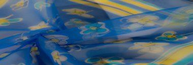 Bulanık efekt, çiçek sarısı ve beyaz desenli, parlak mavi renkli yumuşak, akan kumaşı güçlendirir. Hafif malzeme, cazibe ve entelektüellik hissi yayar..