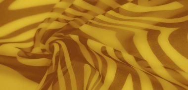 Kahverengi soyut desenli sarı kumaşın bulanık sanatsal görüntüsü. Yakın plan gölgeler karmaşık dokular, pürüzsüz kıvrımlar, ve canlı bir renk paleti.