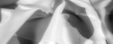 Tarafsız ve sanatsal soyut kompozisyonlar için ideal, dinamik kıvrımlar ve gölgeler gösteren, gri tonda yumuşak, dokulu bir kumaş..