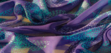 Renk ve dokuların karışımı bunu sanatsal ve moda projeleri için ideal bir seçim haline getirmektedir ve turkuaz desenli canlı bir mor kumaş ışığı güzel bir şekilde yakalar.