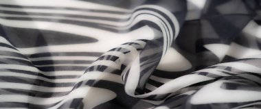 Kıvrımlı dalga desenleri olan katmanlı siyah beyaz kumaş. Sanatsal kıvrımlar ve asgari doku ona dinamik ve zarif bir görsel stil kazandırıyor..